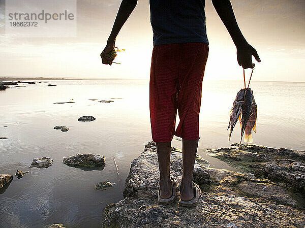 Ein kleiner äthiopischer Junge hält seinen frischen Fang am Ufer des Langano-Sees in Äthiopien.
