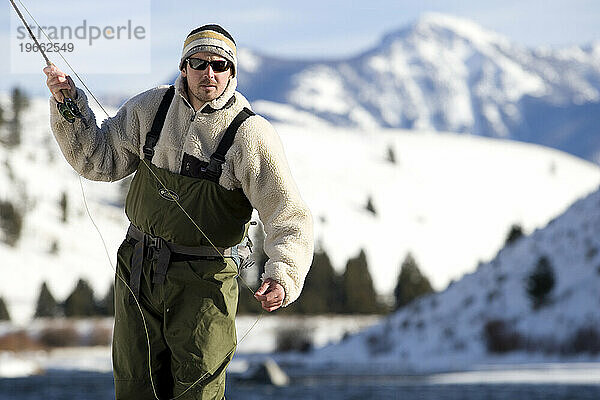 Ein Mann beim Fliegenfischen an einem Wintertag.