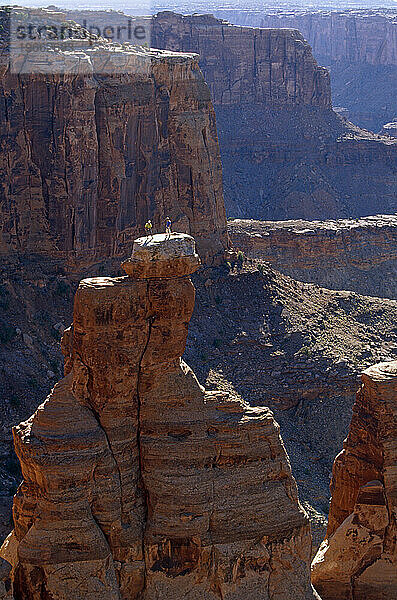 Zwei Kletterer stehen auf dem Gipfel eines Wüstenturms in Utah