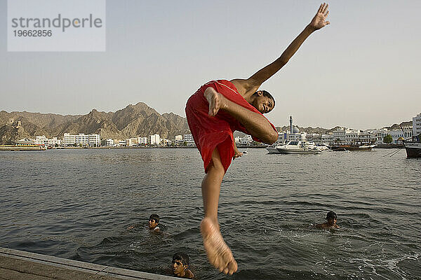 Ein Junge taucht ins Wasser des Hafens Sultan Qaboos in Maskat  Oman.