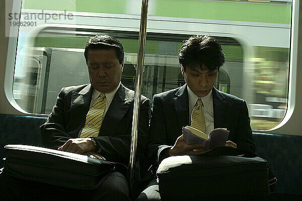 Zwei Männer sitzen in einem Zug in Tokio  Japan.