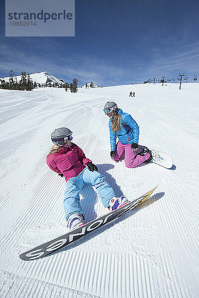 Zwei Snowboarderinnen haben Spaß daran  Snowboarden zu lernen.
