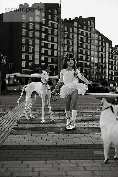 Mädchen mit weißem Hund auf einem Spaziergang in der Stadt.