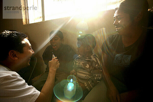 Ein amerikanischer Arzt lacht mit einer mexikanischen Familie während einer Untersuchung in Tecate  Mexiko.