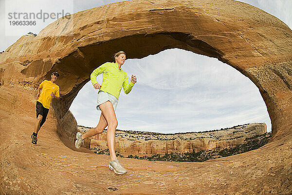 Zwei Menschen laufen unterhalb des Wilson Arch in der Nähe von Moab  Utah.