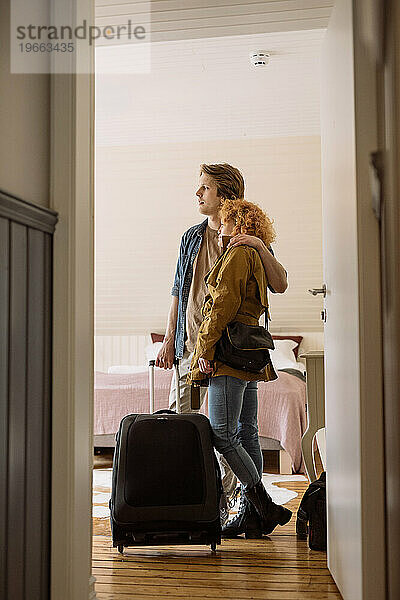 Glückliches Paar mit Koffer im Hotelzimmer