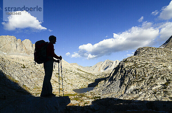 Die Silhouette eines Rucksacktouristen mit Trekkingstöcken  der vom Cirque Pass auf der Sierra High Route  Kalifornien  hinunterblickt.