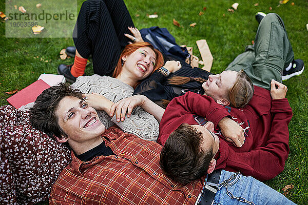 Lachende Freunde  die auf dem Gras liegen