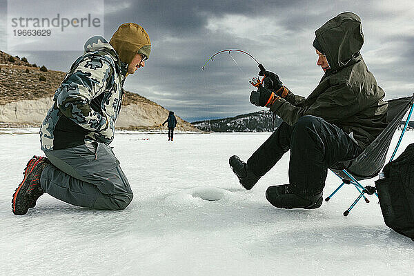 Familieneisfische im winterlichen Outdoor-Abenteuer auf dem zugefrorenen See