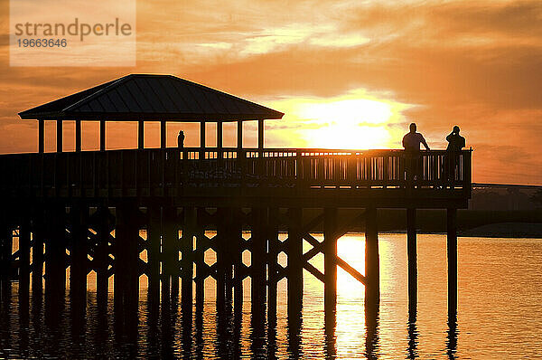 Eine Silhouette zweier Männer  die bei Sonnenuntergang auf Hilton Head Island  SC  auf einem Pier am Intracoastal Waterway stehen.