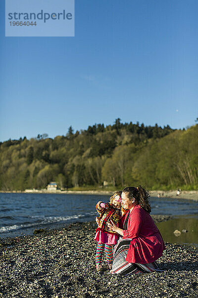 Mutter und kleine Tochter entspannen sich am felsigen Küstenstrand  Seattle  Washington  USA