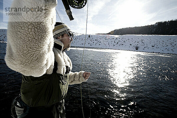 Ein Mann beim Fliegenfischen an einem Wintertag.