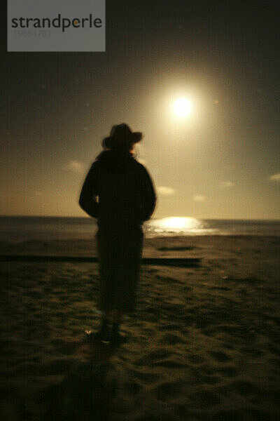 Eine Frau steht nachts als Silhouette an einem Strand in Bolinas  Kalifornien. (Weicher Fokus)