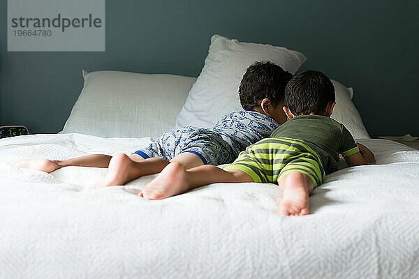 Jungen lesen ein Buch auf einem gemütlichen Bett.