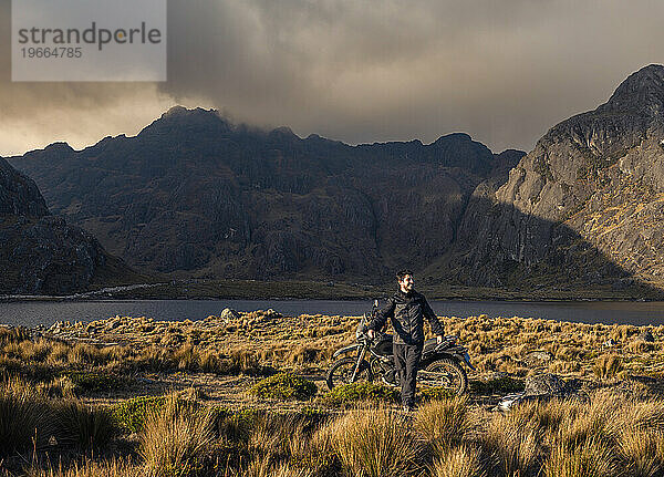 Abenteuer-Motorradfahrer auf Berg und See von Peru bei Sonnenuntergang