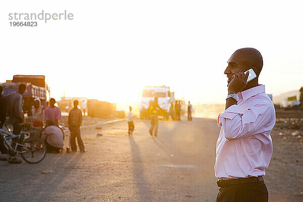 Ein junger Mann geht in Äthiopien eine Straße entlang und benutzt dabei sein Mobiltelefon.