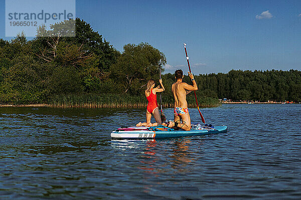 Freunde haben Spaß am Waldsee und fahren SUP-Boards. Paddleboarding.
