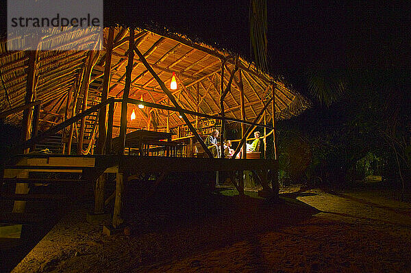 Menschen entspannen sich in einem Bungalow im karibischen Resort unter freiem Himmel.
