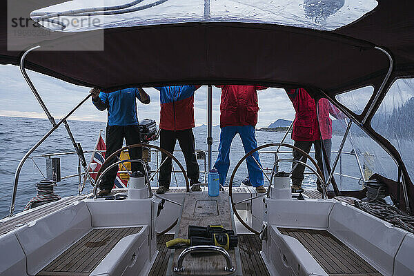 4 Personen in bunter Kleidung auf dem Heck eines Segelboots  Lofoten-Inseln  Norwegen
