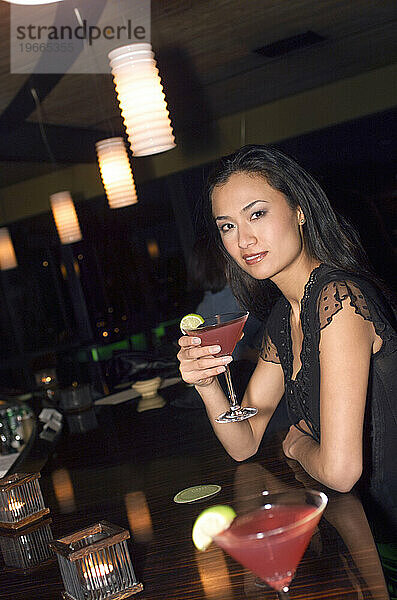 Eine Frau an einer Bar mit einem Cocktail.