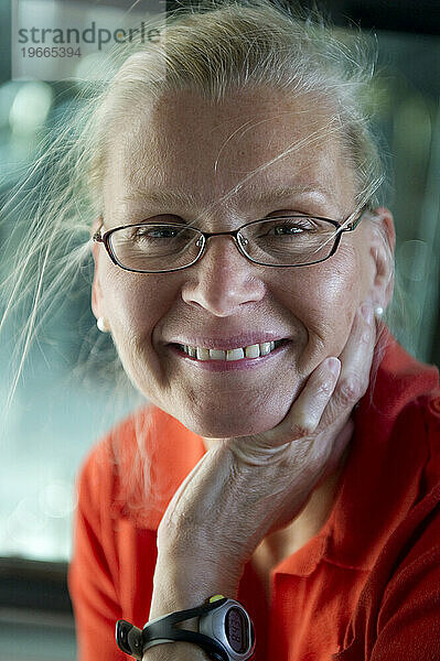 Eine blonde Frau mit Brille lächelt strahlend.