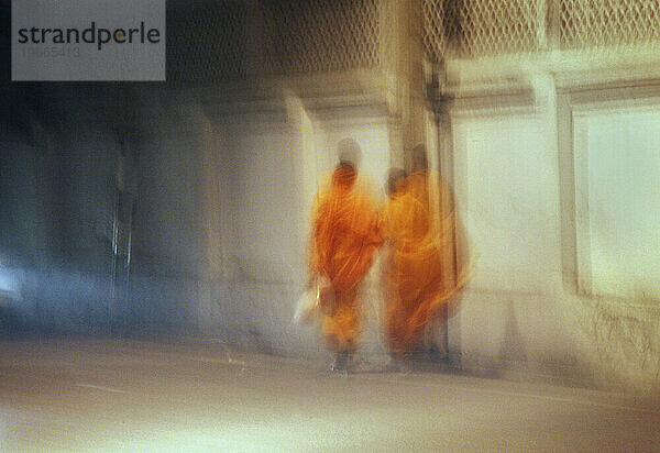 Zwei buddhistische Mönche gehen nachts durch die Straßen. Chiang Mai  Thailand. (Bewegungsunschärfe)