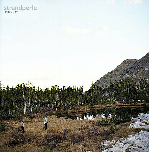 Ein Mann und eine Frau laufen in der Nähe eines kleinen Alpensees im Hinterland von Colorado.
