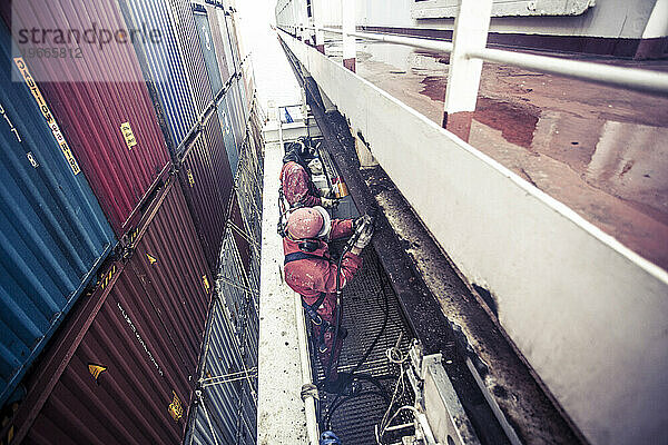 Arbeiter warten auf See ein Containerschiff
