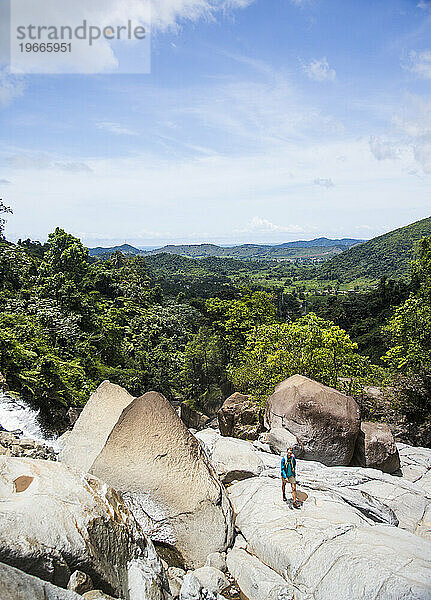 Eine junge Frau geht auf einem Felsen mit Blick auf den Dschungel von Puerto Rico.