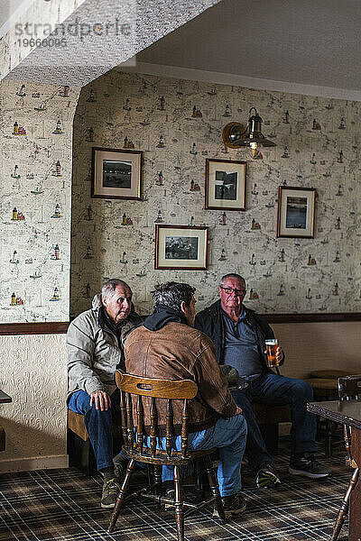 Drei Männer genießen ein Pint im örtlichen Pub  Portree  Isle of Skye  Schottland  Großbritannien