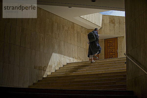 Ein Mann in traditioneller nahöstlicher Kleidung geht die Treppe einer großen Moschee hinauf.