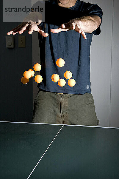 Ein Mann gibt vor  zu zeigen  dass er in der Lage ist  10 Tischtennisbälle auf einmal schweben zu lassen.