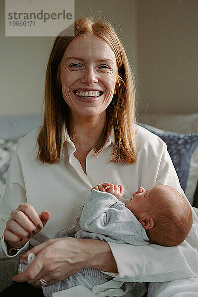 Mutter lacht und lächelt und hält ihr neugeborenes Baby in purer Freude