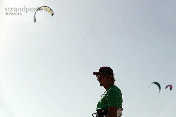 Ein Mann beobachtet seine Schüler beim Kitesurfenlernen.