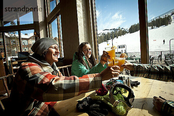 Drei Freunde trinken ein Bier in einer Hütte in einem Skigebiet.