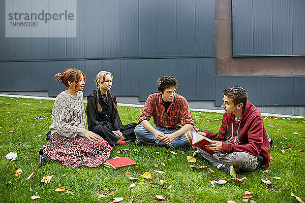 Studenten lesen ein Buch im Innenhof des Campus