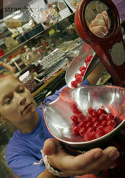 Eine Arbeiterin in einem Süßwarenladen wiegt die Kieferbrecher  die ein Kunde kauft.