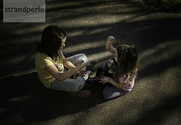 Schwestern spielen draußen Stein und Papierschere
