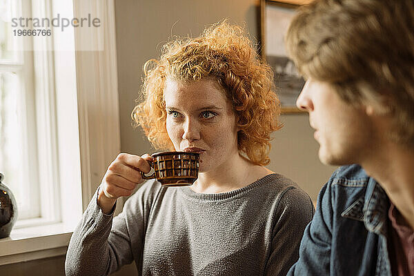 Junge Frau trinkt Kaffee  während sie mit einer Erntefreundin sitzt