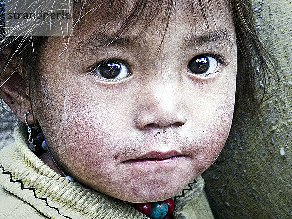Ein junges nepalesisches Mädchen starrt in Ostnepal in die Kamera.