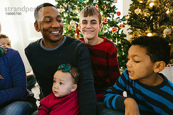 Schwarzer Vater  Söhne und kleines Mädchen glücklich zusammen mit Weihnachtsbäumen