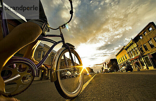Eine Frau fährt bei Sonnenuntergang mit dem Fahrrad durch eine Stadt.