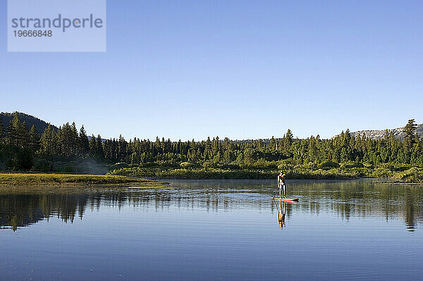 Ein Mann beim Stand Up Paddleboards (SUP) am Lake Tahoe in einer wunderschönen ruhigen Umgebung  Kalifornien.