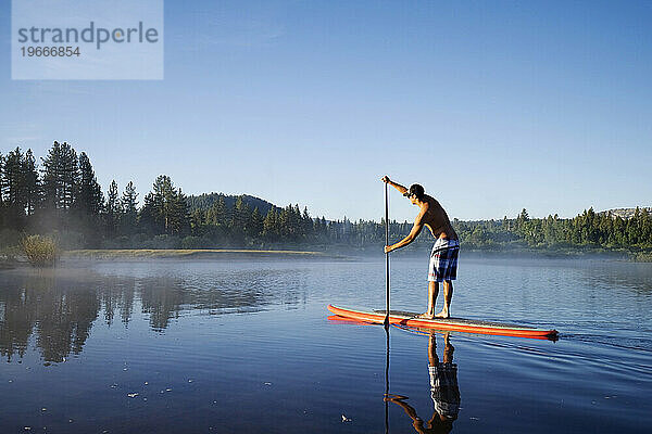 Ein Mann beim Stand Up Paddleboards (SUP) am Lake Tahoe in einer wunderschönen ruhigen Umgebung  Kalifornien.