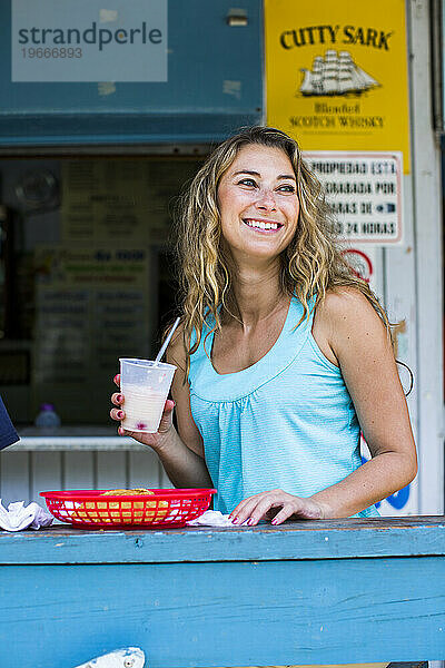 Eine junge Frau lächelt  während sie an der Bar eines kleinen Restaurants in Puerto Rico sitzt.