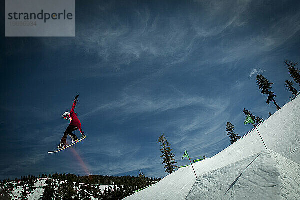 Snowboarderin springt von einem Sprung ab.