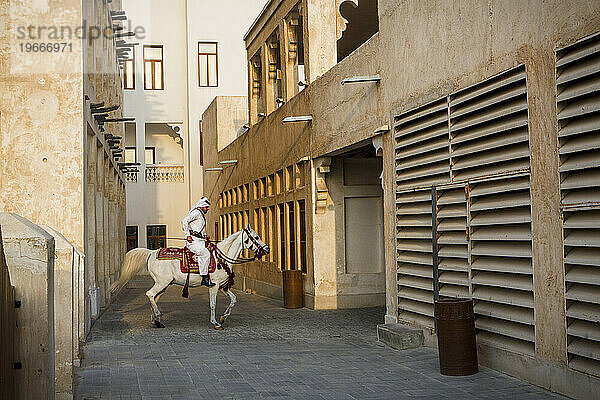 Mann in traditioneller arabischer Kleidung reitet Pferd im Souq Waqif  Doha  Katar