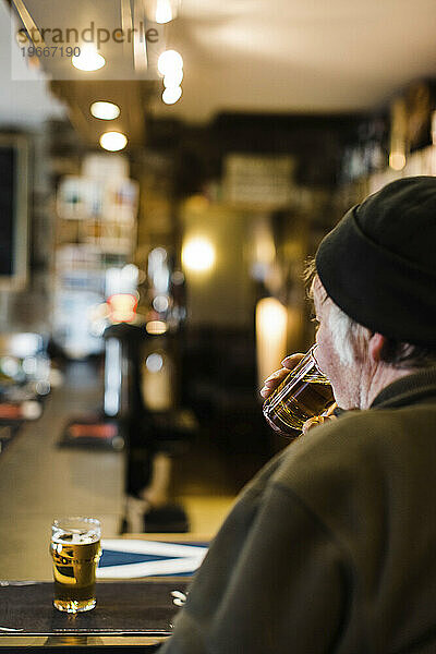 Rear view of older man enjoying glass of beer at pub  Scotland  UK