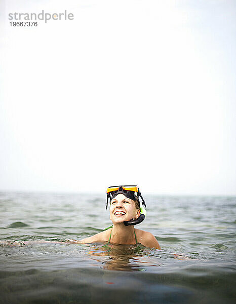 A woman smiles with a snorkel and mask on her head.