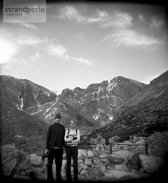 Two hikers stand still for a portrait with Longs Peak  the highest peak in Rocky Mountain National Park  Colorado.